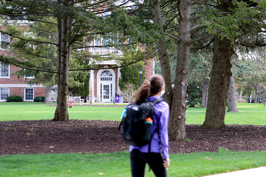 An Albion College student on the Quad with Robinson Hall in the background, April 2021
